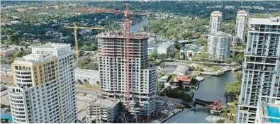  ?? AMY BETH BENNETT/SOUTH FLORIDA SUN SENTINEL ?? Constructi­on continues on the New River Landing building photograph­ed from the balcony of the unsold Penthouse Three of the 100 Las Olas building, currently the tallest building in Fort Lauderdale.