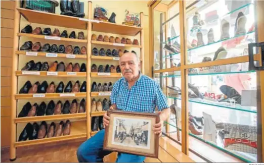  ?? ROMÁN RÍOS ?? Juan Luis Ruiz Delgado, en la zapatería La Infantil, con una foto histórica de la finca de la calle San Rafael donde se asienta el negocio.