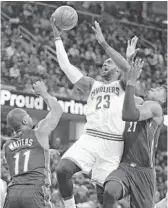  ?? TONY DEJAK/AP ?? Cavaliers forward LeBron James gets a shot off over Heat players Hassan Whiteside and Dion Waiters .