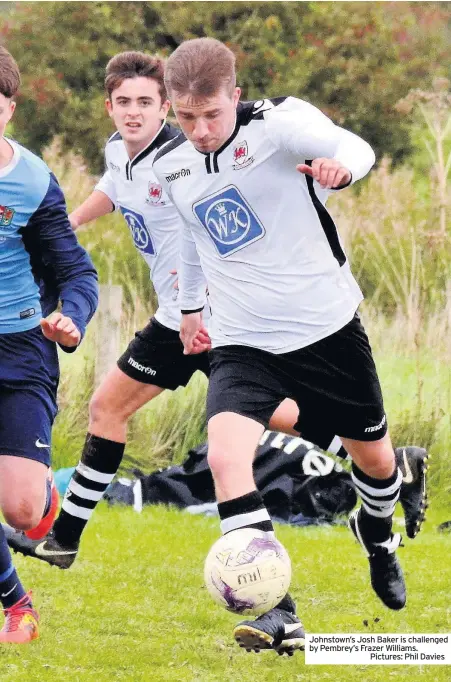  ??  ?? Johnstown’s Josh Baker is challenged by Pembrey’s Frazer Williams.Pictures: Phil Davies