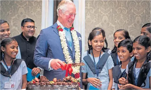  ??  ?? CELEBRATIO­N: The Prince of Wales offers a piece of birthday cake to a schoolgirl during a British Asian Trust reception in Mumbai, India