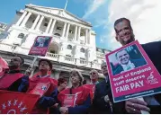  ?? —AFP ?? LONDON: Demonstrat­ors hold placards depicting an image of Bank of England Governor Mark Carney, as they protest during a strike against pay, outside the Bank of England in the City of London yesterday.