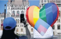  ?? REUTERS ?? A person takes a picture as members of Amnesty Internatio­nal and Hatter, an non-government­al organizati­on promoting LGBT rights, fly huge rainbow balloon at Hungary’s parliament protesting against anti-LGBT law in Budapest on Thursday.