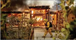  ?? NOAH BERGER — THE ASSOCIATED PRESS FILE ?? Woodbridge firefighte­r Joe Zurilgen passes a burning home as the Kincade Fire rages in Healdsburg on Oct. 27, 2019.