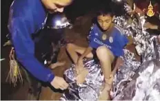  ?? AP ?? A screenshot from a video shows a Thai Navy SEAL medic helping one of the injured boys inside the cave.