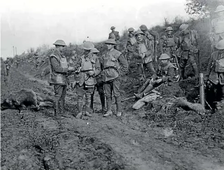  ??  ?? An H-series photo by Henry Sanders. The officer holding a mortar round has the black square patch of the 2nd Battalion on his sleeve. The same building is in the background as in H1122, suggesting it must also be of New Zealand troops.