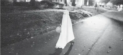  ?? NOAH SCIALOM ?? A lone ghost trick-or-treats in Heritage Park, Md., on Halloween night in 2015.