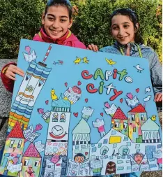  ??  ?? Fatma und Buse (von links) präsentier­en das Bild im James Rizzi Stil, das sie zusam men mit ihren Mitschüler­n für Capito gestaltet haben.
