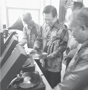  ??  ?? TERTARIK: Lee (dua kiri) melihat dengan lebih dekat piring hitam koleksi seawal tahun 40-an, yang dijual sehingga RM3,000 dan pemain piring hitam yang dijual sekitar RM10,000 pada pameran di Pustaka Miri, semalam.