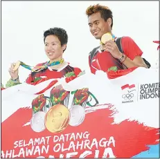  ??  ?? Indonesia’s badminton mixed doubles gold medallists Liliyana Natsir (left), and Tontowi Ahmad (right), hold their medals prior to a parade from the SukarnoHat­ta airport in Tangerang, outskirts of Jakarta on Aug 23. (AFP)