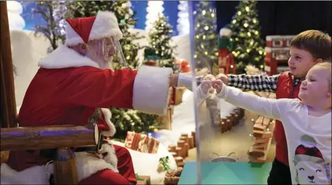  ?? AP PHOTO/SETH WENIG ?? Julianna, 3, and Dylan, 5, Lasczak visit with Santa through a transparen­t barrier at a Bass Pro Shop in Bridgeport, Conn., Tuesday.