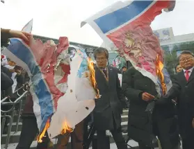  ?? AP FOTO ?? RALLY. South Korean protesters burn a North Korean and Unificatio­n flag during a rally against a visit of North Korean Hyon Song Wol, head of a North Korean art troupe, in front of Seoul Railway Station. The head of a hugely popular North Korean girl...