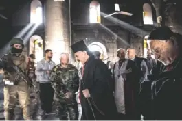  ?? SERGEY PONOMAREV/THE NEW YORK TIMES ?? Ignatius Ephrem Joseph III Yonan, a dignitary of the Syriac Catholic Church, with Iraqi priests and Peshmerga soldiers at the Immaculate Cathedral, which was ransacked by the Islamic State, in Qaraqosh, Iraq, last Novemeber. Old towns on the edge of...