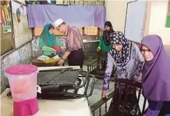  ??  ?? YUSRI bersama guru mengemas perkakas sekolah ditenggela­mi banjir.