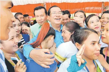  ??  ?? Hun Sen (centre) poses for a picture during a ceremony at a compound of factories in Phnom Penh. — AFP photo