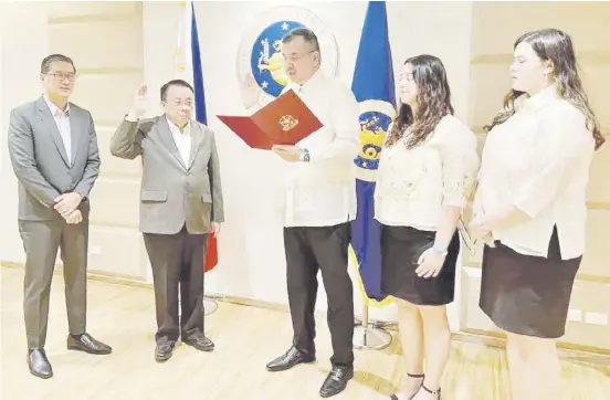  ?? PHOTOGRAPH COURTESY OF PSC ?? RICHARD ‘Dickie’ Bachmann (middle) gets officially sworn in by Executive Secretary Lucas Bersamin (second from left) as the 12th chairman of the Philippine Sports Commission. Also shown are Senior Deputy Executive Secretary Hubert Guevarra (left) and Bachmann’s daughters Ciara and Sophia.