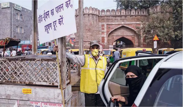  ?? Reuters ?? A volunteer holds a placard with informatio­n regarding restrictio­ns on private vehicles based on registrati­on plates in New Delhi on Monday.
