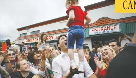  ?? COLE BURSTON/GETTY IMAGES ?? Liberal Leader Justin Trudeau balances a child during a campaign stop alongside local candidate Andrea Kaiser, right, in Niagara Falls, Ont., on Monday. Taking responsibi­lity for errors in judgment means owning up to something and accepting the consequenc­es, Christie Blatchford writes.