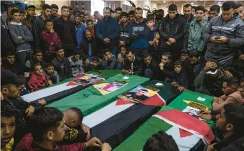  ?? FATIMA SHBAIR/AP ?? Mourners gather around the coffins of four out of eight Palestinia­n migrants who died off the Tunisian coast, at their funeral Dec. 18 at a mosque in Rafah in the Gaza Strip. A growing number of Gazans, seeking better lives, are dying at sea.