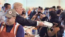  ??  ?? Trump passes out hot dogs in Red Cross containers to storm victims at the NRG Center in Houston on Saturday.