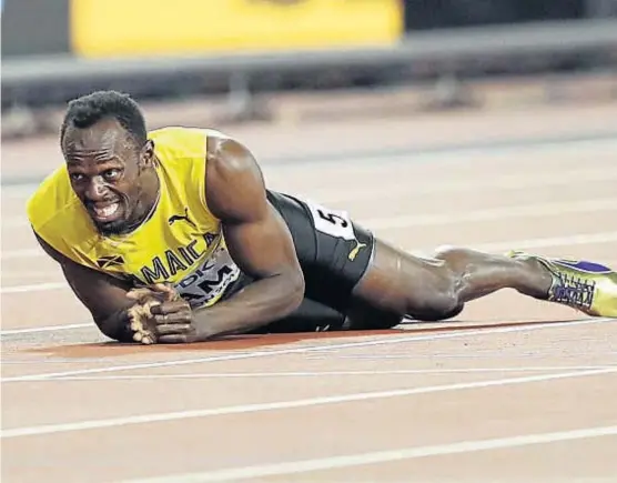  ?? (AP) ?? El peor final. Usain Bolt terminó tendido sobre la pista sin poder soportar el dolor. Sus compañeros y el público lo apoyaron siempre.