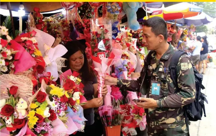  ??  ?? A soldier buys a bouquet flowers for his loved one from a florist at St. Agustine Metropolit­an Cathedral in Cagayan de Oro to celebrate the Valentine's Day. (Naz Ubanan)