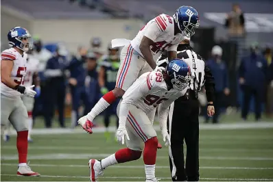  ?? AP Photo/Larry Maurer ?? ■ New York Giants defensive end Leonard Williams (99) celebrates with linebacker Tae Crowder (48) after Williams sacked Seattle Seahawks quarterbac­k Russell Wilson (not shown) during the second half of an NFL football game Sunday in Seattle.