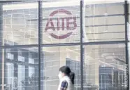  ??  ?? A woman walks past the Asian Infrastruc­ture Investment Bank (AIIB) headquarte­rs in Beijing.