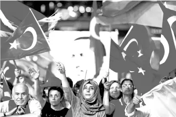  ?? — Reuters photo ?? File photo shows supporters of Turkish President Recep Tayyip Erdogan wave national flags as they listen to him through a giant screen in Istanbul’s Taksim Square.