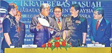  ??  ?? Ahmad Zahid shows the pledge signed by Mustafar (left) to Azam. Also seen are deputy home ministers Datuk Nur Jazlan Mohamed (third right) and Datuk Masir Kujat, and Home Ministry secretary-general Datuk Seri Alwi Ibrahim (right). — Bernama photo