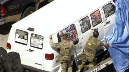  ?? WPLG-TV VIA AP ?? FBI agents covering a van after the tarp fell off as it was transporte­d from Plantation, Fla., on Friday that federal agents and police officers have been examining in connection with package bombs that were sent to high-profile critics of President Donald Trump. The van has several stickers on the windows, including American flags, decals with logos and text.