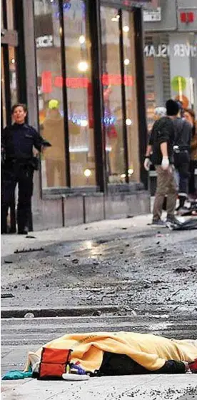  ??  ?? Aftermath: A medic walks among bodies of the victims strewn across the street yesterday