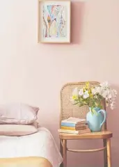  ?? ?? Muted sunset and ocean tones invoke calm and relaxation. Wall painted in Resene Sakura, jug vase in Resene Fountain Blue and painted books in Resene Fountain Blue and Resene Hot Toddy. Chair from Cintesi, bedlinen from Foxtrot Home, artwork by Carmel Van Der Hoeven.