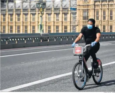  ?? ANDY RAIN / EFE ?? Un hombre con mascarilla y guantes cruza en bicicleta el Puente de Westminste­r, ayer en Londres.