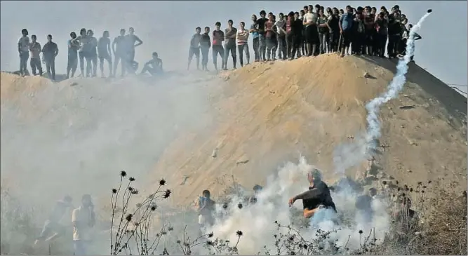  ?? MOHAMMED SALEM / REUTERS ?? Un joven palestino devuelve un bote de humo a las fuerzas israelíes que intentan alejarlo de la zona de exclusión en la franja de Gaza
