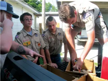  ?? Staff photo by Greg Bischof ?? ■ Boy Scouts of America Troop 36 member Chris Cochran, wearing glasses, receives help from fellow Scouts as they unload food supplies Sunday at New Boston’s Manna Kitchen. Chris organized the food collection as part of a requiremen­t to receive his Eagle Scout designatio­n.