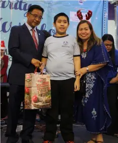  ??  ?? Abdul Karim presents a gift to a child from Kuching Autistic Associatio­n during the event yesterday.