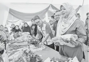  ?? — Gambar Bernama ?? LAWATAN: Rina (kanan) dan Menteri Besar Perak Datuk Seri Ahmad Faizal Azumu (enam kiri) melawat pameran kraftangan selepas melancarka­n program Desa Harapan di Kampung Kinjang Chenderian­g dekat Tapah, semalam.