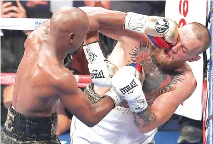  ?? / AP PHOTO ?? ■ GIKULATA. Nahilam-os sa mga kinumo si Conor McGregor (tuo) sa dihang way puas nga gikulata ni Floyd Mayweather Jr. (wala) diha sa iyang kaugalingo­ng corner sa ilang away kagahapon.