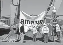  ?? MAX GERSH/
THE COMMERCIAL APPEAL ?? Workers take down a banner Jan. 27, 2020, after a ceremony for a new Amazon fulfillment center in Memphis.