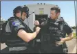  ??  ?? Officer Daniel Bristow helps officer Robert Rench with his gear.