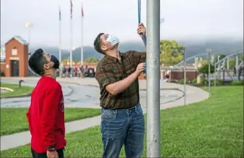  ?? Andrew Rush/Post-Gazette ?? Eleventh grader Ricardo Lopez, left, and 10th grader Justin Couch raise the flag as a part of ROTC’s flag detail outside at Ambridge Area Senior High School on Tuesday, the first day of Pennsylvan­ia’s mask mandate for K-12 schools and day care centers.