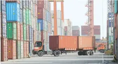  ??  ?? TRUCKS driving past rows of cargo containers at the port in Manila