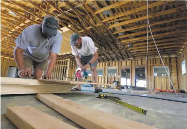  ?? Eric Gay / Associated Press ?? James Wheeler Jr. (right) cuts wood last month to help rebuild his fishing business in Port Aransas, Texas.