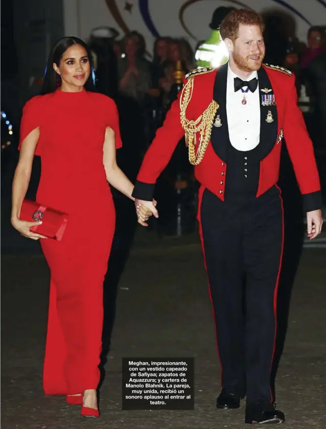  ??  ?? Meghan, impresiona­nte, con un vestido capeado de Safiyaa; zapatos de Aquazzura; y cartera de Manolo Blahnik. La pareja, muy unida, recibió un sonoro aplauso al entrar al teatro.