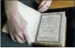  ?? STEVEN SENNE — THE ASSOCIATED PRESS ?? Massachuse­tts Institute of Technology archivist Nora Murphy places a second edition of the Eliot Indian Bible on a table at the MIT rare book collection, in Cambridge, Mass.