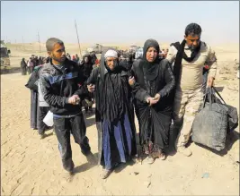  ?? KHALID MOHAMMED/ THE ASSOCIATED PRESS ?? An Iraqi army soldier helps displaced civilians Sunday as they flee their homes due to fighting between Iraqi security forces and Islamic State militants in Mosul, Iraq.