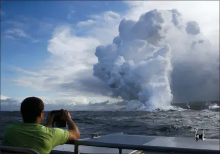  ?? JAE C. HONG — THE ASSOCIATED PRESS ?? In this file photo, Joe Kekedi takes pictures as lava enters the ocean, generating plumes of steam near Pahoa, Hawaii.