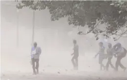  ?? — BIPLAB BANERJEE ?? People caught in a sudden dust storm in New Delhi on Wednesday. A squall and dust storm, accompanie­d by scattered light rains, lashed parts of the city, providing respite from the heat.