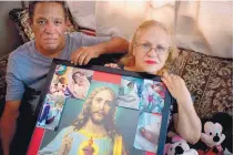  ?? RAMON ESPINOSA /ASSOCIATED PRESS ?? Maria Gonzalez Munoz, right, and Juan Manuel Gonzalez pose in San Juan, Puerto Rico, earlier this month with an image of Jesus surrounded by photos of Munoz’s sister Ramona taken during her illness and funeral.